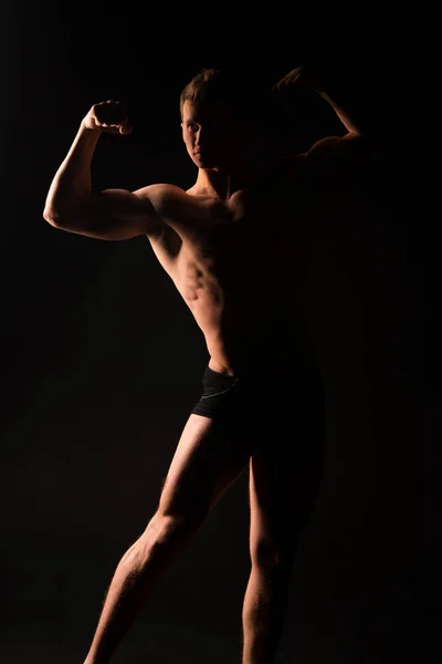 Silhouet van gespierde atleet, EE en licht. Man met sexy fit lichaam geïsoleerd op zwarte achtergrond. Bodybuilder met kale romp. fitness model weergegeven: sterke spieren, sport en gezondheid concept — Stockfoto