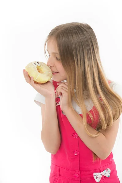 Criança olha para donut isolado em branco. Menina com donut de anel envidraçado. Um miúdo com comida de plástico. Alimentação insalubre e lanche. Minha refeição favorita — Fotografia de Stock