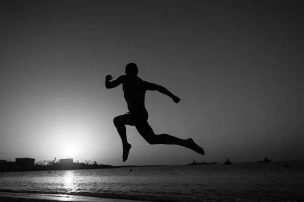 Kör man. silhuetten av kör man på sunset brinnande himmel bakgrund i havet, sport och fritid, framtid och framgång, människor och natur, hastighet och hälsosam livsstil — Stockfoto