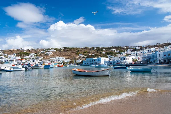Mykonos, Greece - May 04, 2010: boats at sea beach. Sea coast on cloudy blue sky. Mediterranean village with houses on mountain landscape. Summer vacation on island. Wanderlust and travel — Stock Photo, Image