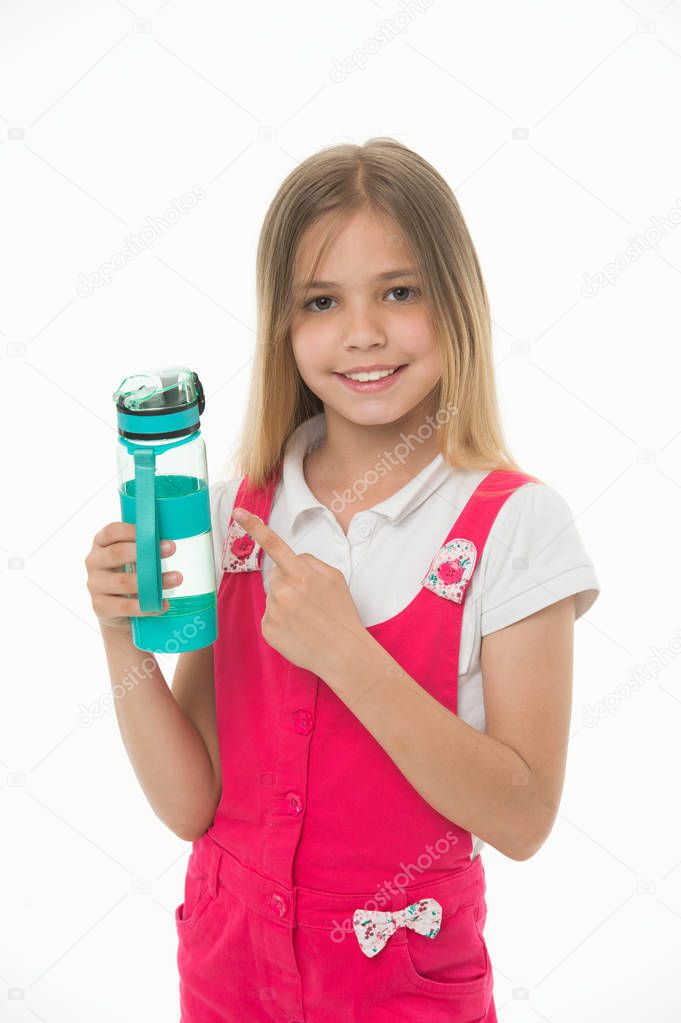 Stay hydrated. Girl cares about health and water balance. Girl on smiling face posing with water bottle isolated white background. Kid girl with long hair pointing at bottle. Water balance concept