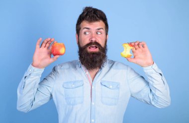 Meyve sağlıklı yemek saati her zaman iyi bir fikir. Adam yakışıklı hipster uzun sakal olgun elma ve neredeyse yenmiş elma güdük tutar. Adam diyet beslenme meyve yiyor. Elma her gün yemek. Mükemmel ve kusur kavramı