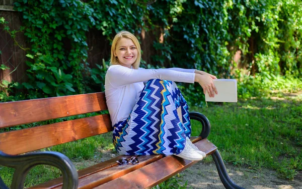 Šťastný konec z ní dělá radost. Lady spokojený drží knihu zahradní slunečný den. Dívka sedí, lavice relaxaci s knihou, pozadí zelené přírody. Čtení může pomoci snížit stres. Právě dokončil čtení — Stock fotografie