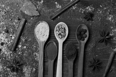 Tahta kaşık pul biber, zerdeçal, kuru otlar, toz tarçın, karabiber toplar ve anason ile. Baharat bileşimi. Mutfağı ve aroma kavramı.