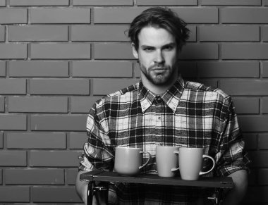 Duvarda bardakları tutan yakışıklı adam.