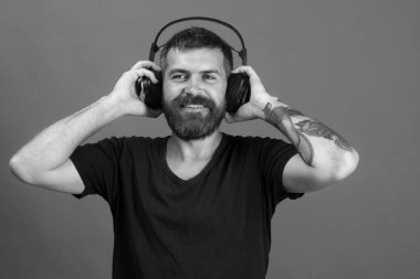 Şarkıcı sakal ve mutlu yüz ile müzik dinliyor. Adam kulaklık mavi arka plan üzerinde tutar. DJ sakallı