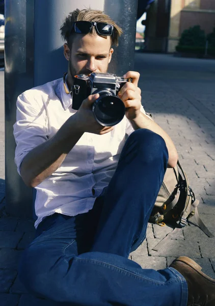 Joven viajero o fotógrafo con cara concentrada sostiene cámara retro. Concepto de fotografía y turismo. El turista toma fotos —  Fotos de Stock