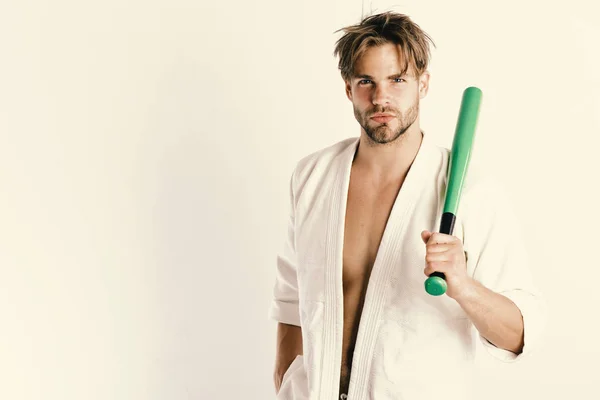 Hombre con cara seria aislado sobre fondo blanco, espacio para copiar. Guy posa en kimono blanco sosteniendo bate de béisbol verde . — Foto de Stock