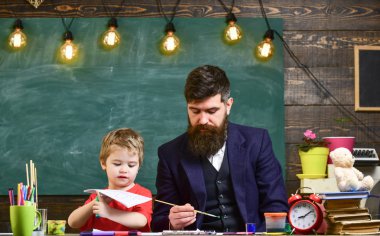 Öğretmen sakal, baba ve küçük oğul çizerken, sınıfta oluşturma, kara tahta arka plan ile. Sanat ders kavramı. Çocuk ve resim, çizim meşgul yüzleri öğretmen