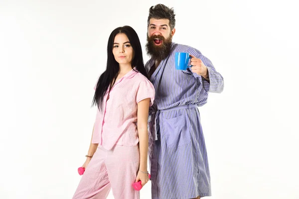 Pijama, bornoz stand beyaz arka plan üzerinde izole aşık çift. Çift, Aile uykulu yüzlere, enerji dolu. Sabah rutin kavramı. Halter, kahve fincanı adamla kızla — Stok fotoğraf