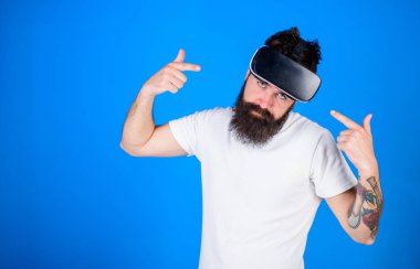 Modaya uygun sakal reklam yeni gadget'ı mavi arka planı olan adam. Hippi serin bakmak ve şık sakal Vr heaset işaret. Dövmeli adam 3D deneyimi, sanal gerçeklik kavramı keyfi sakallı