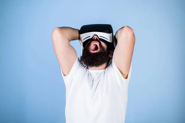 3D design concept. Architect or engineer with virtual reality glasses. Man with beard in VR glasses shocked and disappointed, light blue background. Guy in helmet works as engineer in virtual reality