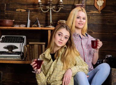 Rahatlatıcı ve mulled şarap içme kızlar. Arkadaşlar rahat kıyafetler içinde sıcak atmosferi, ahşap iç tadını çıkarın. Gülümseyen yüzler kareli giysiler rahatlatıcı arkadaşlar. Tatil ve tatil kavramı