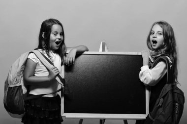 Okul çantası takan çocuklar parlak tahtaya yaslanıyor, kopyalama alanı