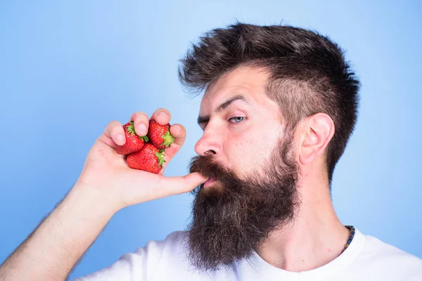 ひげを生やしたヒップスターは、ジュースのボトルとしてイチゴ拳を保持しています。男は、飲むわら青い背景としてイチゴ ジュースを吸う親指を飲みます。男厳格な顔では、新鮮な飲み物いちごジュースをお楽しみください。フレッシュ ジュースの概念 — ストック写真