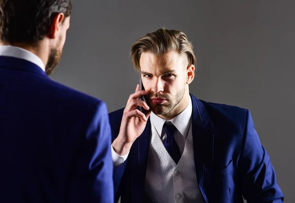 Çekici tıraşsız adam şık giysiler giyer, akıllı telefon tutar — Stok fotoğraf