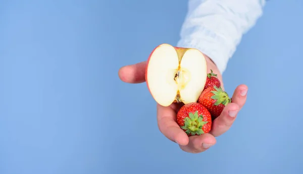 자신을 도울. 손으로 받아 딸기와 사과 과일을 제안합니다. 딸기와 애플 파란색 배경의 절반 남자 손. 과일 유기농 치료 또는 간식입니다. 잘 익은 과일의 신선한 수확 — 스톡 사진