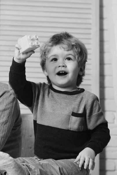 Niño juega con bloques de plástico de colores. Niño pequeño con cara curiosa —  Fotos de Stock