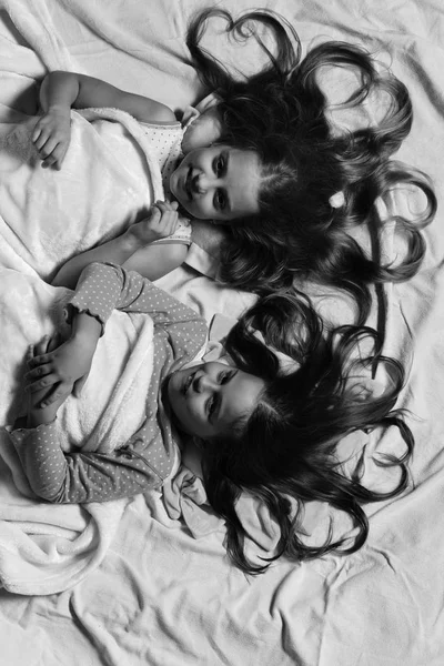 Kızlar pembe yatak çarşafları arka plan üzerinde yalan söyler. Pijamalı kız öğrenciler — Stok fotoğraf
