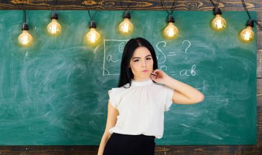 Bayan öğretmen sakin yüzünde kara tahta önünde duruyor. Beyaz bluz uzun saçlı kadın sınıfta durumda. Elit okul kavramı. Öğretmen ders, kopya alanı başlatmak için hazır