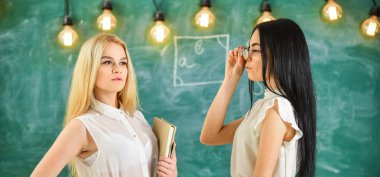 Çekici öğretmen sınıfları sonra overworking. Bayanlar özel ders, kara tahta arka plan başlamak için hazır. Kitap ve çekici görünümlü gözlük ile formal giyim öğretmenler. Özel ders kavramı