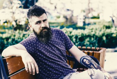 Dinlenmek ve rahatlamak kavramı. Rahatlatıcı, kentsel arka plan taze saç kesimi olan sakallı adam. Hipster güneşli bir gün parkta tadını çıkarın. Sakal ve bıyık katı yüz oturur parkta bankta üzerinde olan adam