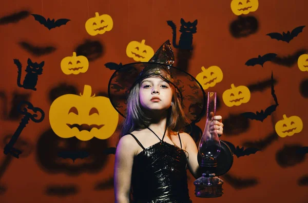 Kind in spooky heksen kostuum houdt oude gas lamp. Haloween partij en decoraties concept. Kleine heks dragen zwarte hoed — Stockfoto
