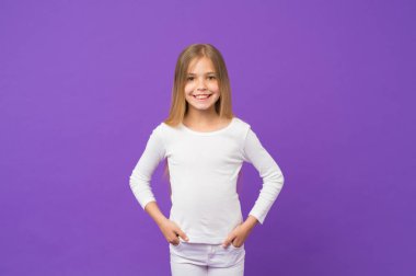 Beyaz jumper ve kot giyen çocuk, gençlik kavramı moda. Uzun parlayan sarı saçlı kız. Güzel çocuk üzerinde mor arka plan izole kocaman bir gülümseme ile. Sevimli yüz ve ela gözlü ile kız öğrenci