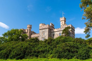 Summer vacation and wanderlust. Castle with green trees in Stornoway, United Kingdom. Lews Castle in garden on blue sky. Victorian style architecture and design. Landmark and attraction. clipart