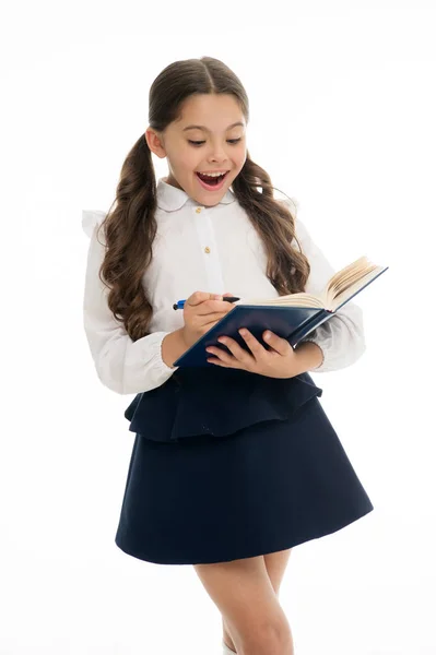Malé dítě s překvapený pohled izolované na bílém. Školačka s dlouhými vlasy drží knihu s perem. Dívka ve školní uniformě, zpátky do školy. Módní génius. Otevřete knihu k životu — Stock fotografie