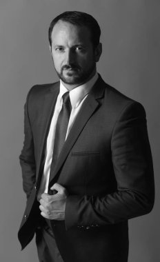 İşadamı akıllı takım elbise ve kravat takıyor. Koyu gri arka plan cep el lider tutar.
