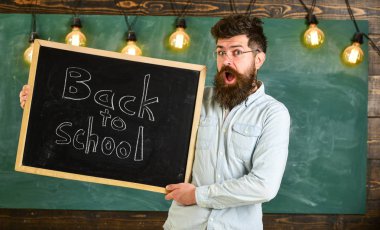 Adam sakal ve bıyık şok yüz memnuniyetle öğrencilerin, kara tahta arka plan ile. Eğitim ve eğitim kavramı. Gözlük öğretmen okul için başlıklı yazı tahtası tutar