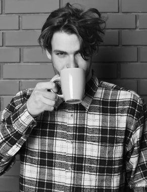 Duvarda fincanı tutan yakışıklı adam.