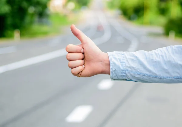 Thumb up gesture try stop car road background. Hand gesture hitchhiking. Make sure you know right gestures to stop car. Thumb up sign not work in many parts of world. Autostop travel. Pick me up