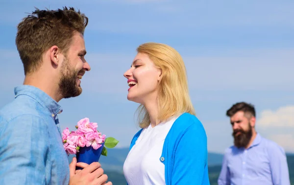 New love. Ex partner watching girl starts happy love relations. Ex husband jealous on background. Couple in love dating outdoor sunny day, sky background. Couple with flowers bouquet romantic date — Stock Photo, Image