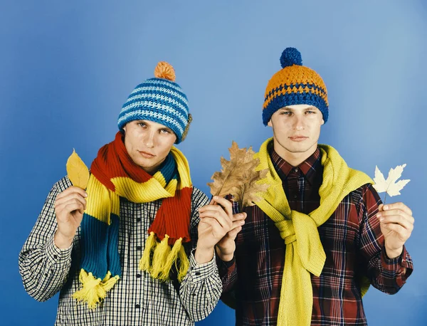 Demi conceito de moda temporada. Homens com rostos sérios no fundo azul. Irmãos gêmeos usando chapéus quentes e cachecóis — Fotografia de Stock