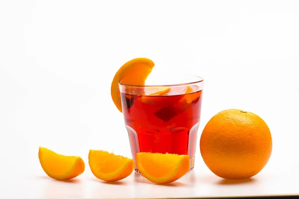 Vaso con bebida de naranja cerca de fruta de naranja jugosa sobre fondo blanco, de cerca. Bebida o bebida con naranja. Cóctel o bebida con zumo de naranja. Concepto de cóctel — Foto de Stock