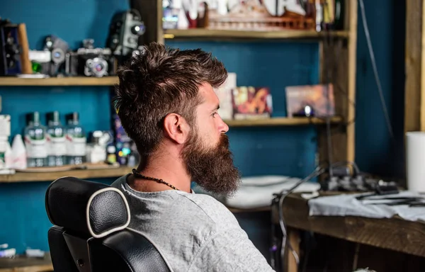 Człowiek z broda i wąsy siedzi w fotelu, fryzjer, zużywalne na tle. Hipster z brodą czeka na fryzjera i fryzura. Człowiek z broda klienta hipster fryzjera. Koncepcja dla zakładów fryzjerskich — Zdjęcie stockowe