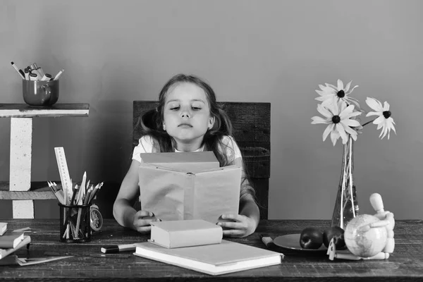 De volta ao conceito de escola e infância. Estudante senta-se na mesa com artigos de papelaria coloridos, livros e flores — Fotografia de Stock