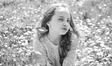 Çocuk ağız gülümseyen karton ile poz. Öpücük kavramı. Yüz öpüşmeyle kız açık havada eğlence harcamak. Kız grassplot, arka planı yeşil çimlere oturur