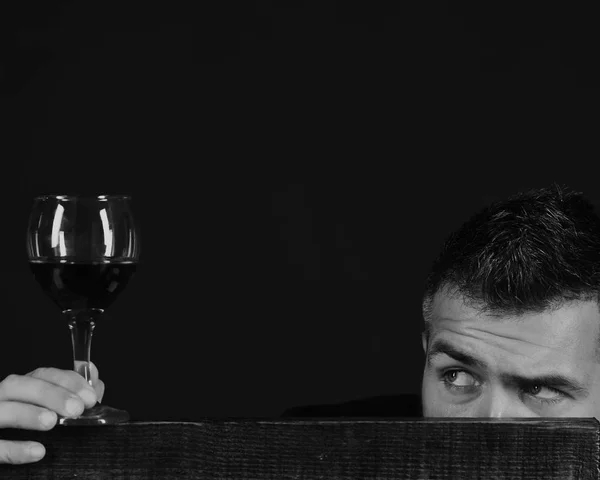 Winetasting and degustation concept. Man with beard holds glass of wine on dark brown background, copy space.