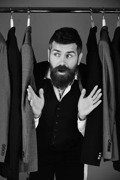 Πωλητής ή βοηθός καταστήματος κρύβεται ανάμεσα στα κοστούμια στις κρεμάστρες ρούχων. — Φωτογραφία Αρχείου