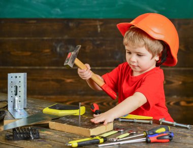 Yürümeye başlayan çocuk meşgul yüzündeki çekiç aracı evde atölye ile oynuyor. Çocuk Çocuk tamirci oynamak. Kask Oluşturucu veya repairer, onarımı veya handcrafting olarak oynayan sevimli çocuk. Handcrafting kavramı