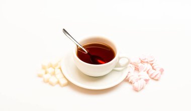 Çay molası kavramı. İçki ve tatlı hazırlanan tatlılar. Kupa siyah çay demlendi, kaşık ve yığın hatmi ve beyaz arka plan üzerinde rafine şeker dolu. Siyah çay ve tatlılar ile kupa