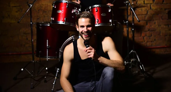 Cantante con la cara alegre canta sentado en escena. Música rock —  Fotos de Stock