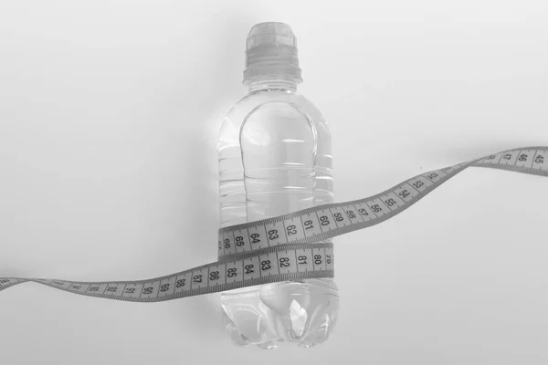 Освежение и символы здорового режима. Бутылка из пластика, обернутая бирюзовой линейкой — стоковое фото
