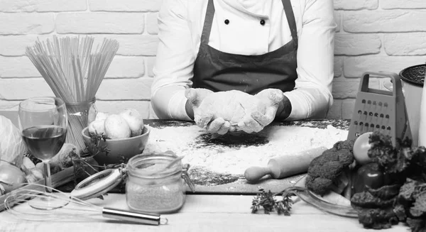 Cook, Burgundia egységes ül, zöldségekkel és konyhai asztal. Férfi kezét dolgozni gyúrt tészta, a fehér háttér — Stock Fotó