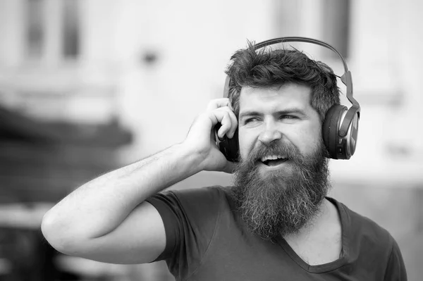 Concept amusant, joyeux et musical. Homme barbu hipster portant de gros écouteurs écoutant de la musique. Jeune homme chantant avec sa chanson préférée tout en marchant dans la ville — Photo