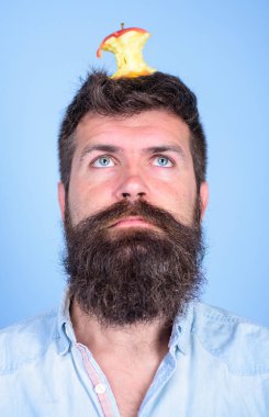 Adam yakışıklı hipster uzun sakal neredeyse kafasına elma güdük hedef olarak yem. Hipster sürpriz elma güdük hedef üzerinde kafa mavi arka plan, yüz kadar yakın. Kilo kaybı gol. Canlı hedef kavramı