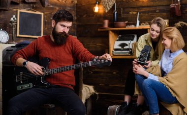 Pişmiş toprak örme kazak ve siyah kot büyük gem taş, moda kavramı ile yüzüğü sakallı adam. Adam elektrik gitarla poz şık sakal ile müzik aletleri promo depolamak.
